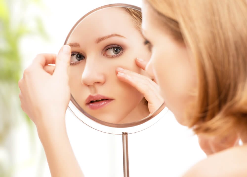 Woman looking at her face in the mirror