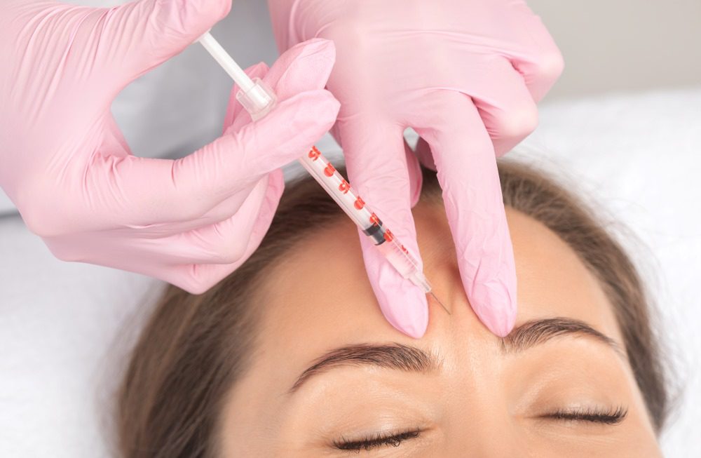 A woman receiving Botox injections in her forehead at a medical spa.