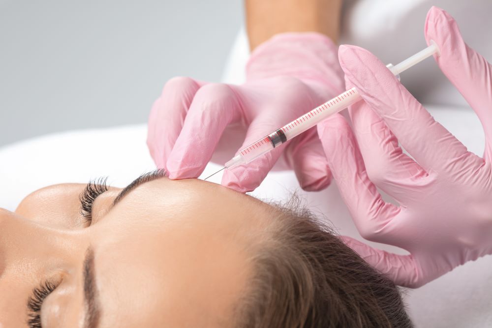 A woman receiving Botox injections in her forehead.