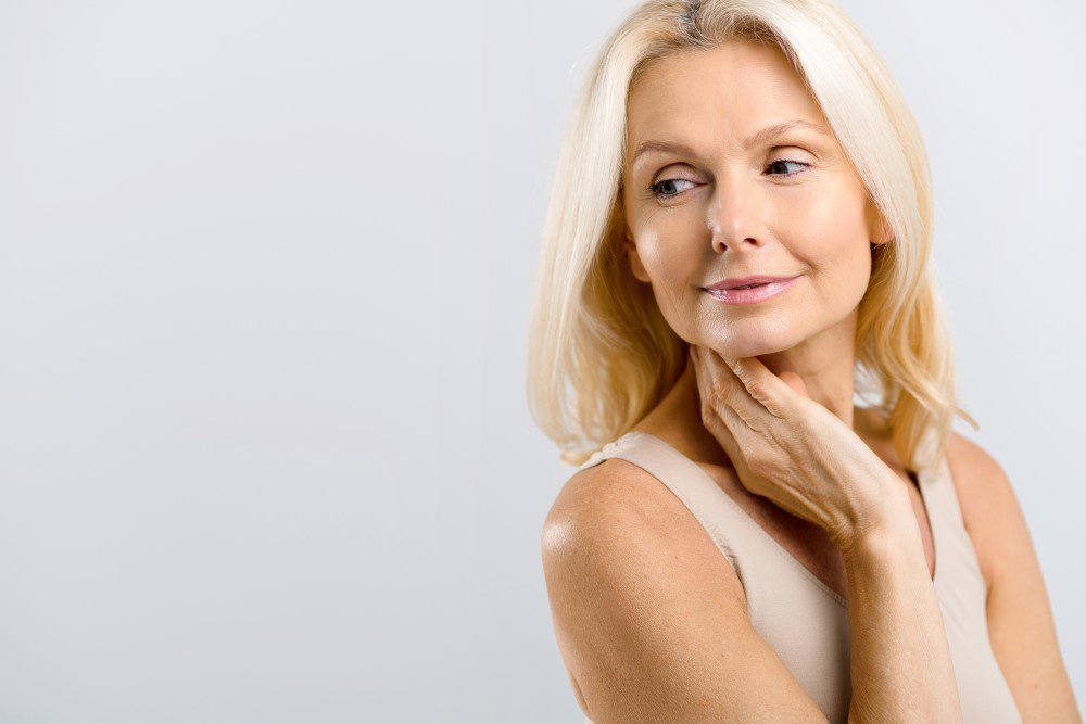 Middle-aged woman posing in studio over grey background.