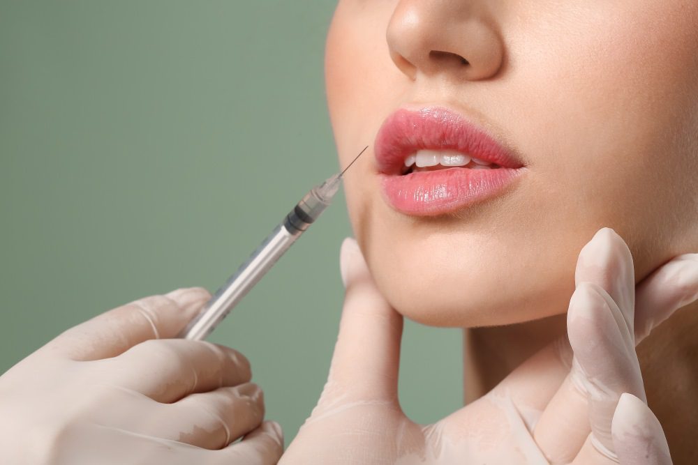 Young woman receiving filler injection in lips.