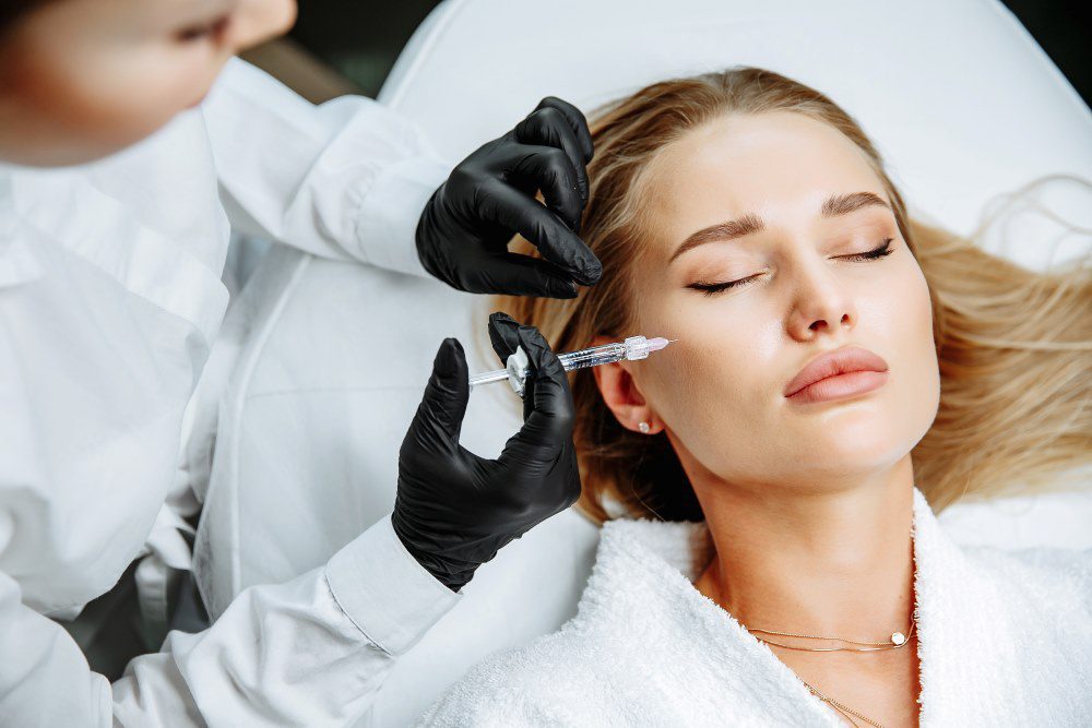 A woman dissolving cheek filler in her face in order to reapply fresh fillers.